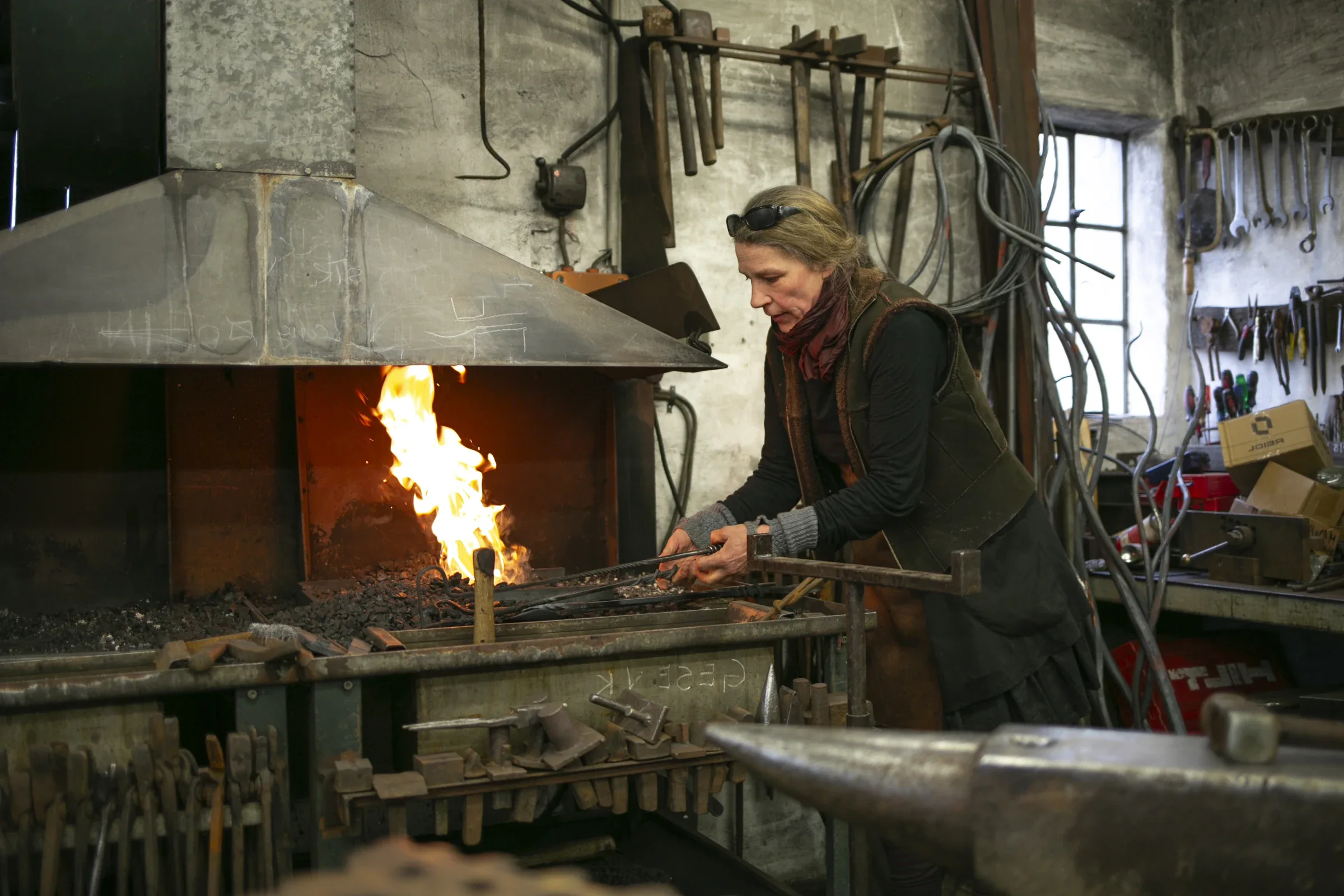 Handwerkerin arbeitet am offenen Schmiedefeuer